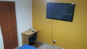 贝洛奥里藏特Hostel Gerais的一间黄色墙壁上配有电视的房间