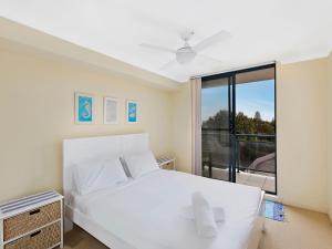 安特兰斯双岸67公寓的卧室设有白色的床和大窗户