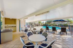 黄金海岸Golden Riviera Absolute Beachfront Resort的一个带桌椅的庭院和一个游泳池