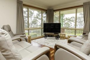 维多利亚山Highland View的客厅配有白色椅子和平面电视