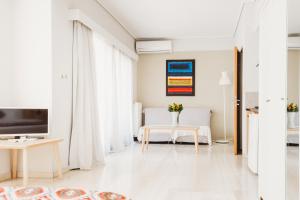 雅典雅典一室公寓的一间配备有电视和桌子的白色客厅