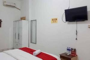 TanjungkarangRedDoorz near Lampung Walk 2的卧室配有一张床,墙上配有电视。
