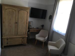 伯明翰埃尔姆登旅馆的一间房间,配有橱柜、两把椅子和一台电视机