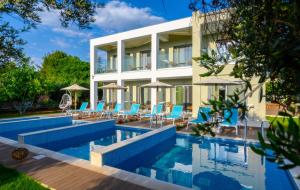 普雷韦扎Alonaki Resort的一座房子,设有一个配有蓝色椅子和遮阳伞的游泳池