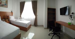 万隆PETA HOSTEL Bandung的酒店客房设有两张床、一张书桌和一个窗户。