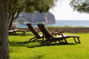 坎亚梅尔坎西蒙内塔酒店 - 仅限成人的坐在靠近海洋的草地上的三把草坪椅