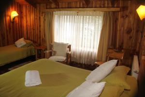 科舒恩克Hosteria-Cabañas Rucapillan的酒店客房设有两张床和窗户。
