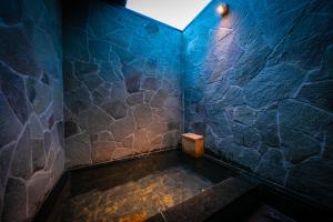 由布市汤布院风之森旅馆的带浴缸的浴室和蓝色石墙