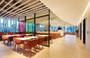 悉尼Holiday Inn Express Sydney Airport, an IHG Hotel的餐厅设有桌椅和大窗户。