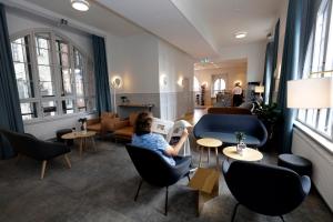 哥本哈根Hotel Bethel的坐在酒店大堂的椅子上读报纸的女人