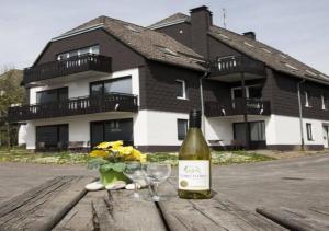温特贝格Ferienpark Winterberg的木桌旁的一瓶葡萄酒和两杯酒