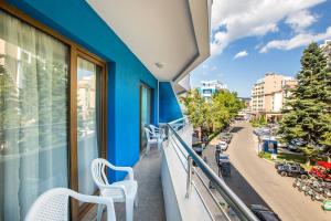 阳光海滩Kuban Resort & Aquapark - All Inclusive的阳台配有2把白色椅子和蓝色墙壁