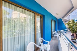 阳光海滩Kuban Resort & Aquapark - All Inclusive的阳台拥有蓝色的墙壁和白色的椅子。