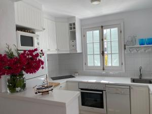 桑特柳伊斯Es Chalet的花瓶里装有白色橱柜和红色鲜花的厨房