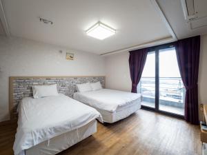 西归浦市济州摹瑟普酒店的带窗户的客房内的两张床