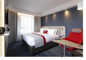 爱丁堡快捷假日爱丁堡市中心酒店的酒店客房,配有一张床和一张红色椅子