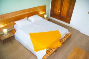 圣多美Sky Nautico Apartment的卧室配有白色的床,上面有黄色的毯子