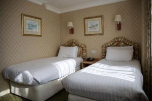 卡莱尔Crown & Mitre Hotel的酒店客房,设有两张床和两张墙上的照片