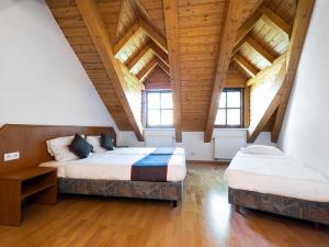 柏林Hotel Bohemia的客房设有两张床铺、木制天花板和窗户。