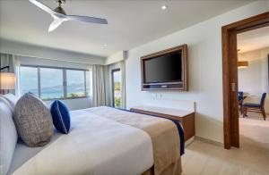 BambooRoyalton Grenada, An Autograph Collection All-Inclusive Resort的一间卧室设有一张大床和一台平面电视。