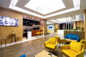 雅西GRAND VIEW Hotel & Suites Copou的大堂设有黄色椅子和酒吧