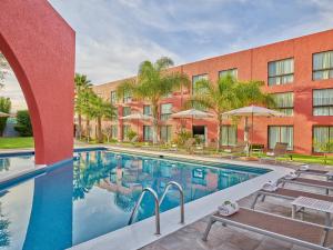 阿瓜斯卡连特斯阿瓜斯卡连特斯嘉年华酒店的一座带椅子的酒店游泳池以及一座建筑