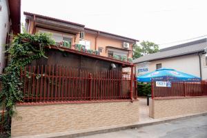 南埃福列Casa Ștefan的一座建筑,有红色的栅栏和蓝色的伞