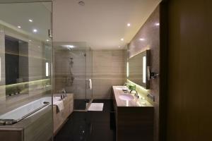 新德里新德里国际机场假日旅馆的浴室配有2个盥洗盆、浴缸和淋浴。