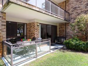 尼尔森湾Bay Parklands 57 ground floor unit with pool tennis court and aircon的阳台的天井配有桌椅