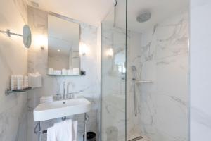 巴黎伯爵夫人酒店的白色的浴室设有水槽和淋浴。
