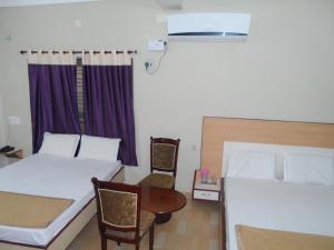 蒂鲁帕蒂Hotel Pasuparthy Residency的一间卧室配有两张床和一张桌子及椅子