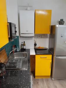伦敦BIG BEN'S SHADE的厨房配有黄色橱柜、水槽和冰箱。