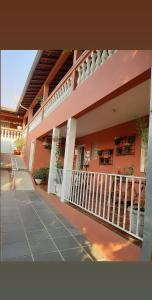 阿瓜斯-迪圣佩德罗Piccola Pousada的粉红色的建筑,设有门廊和阳台