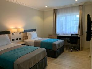特木科Hotel Diego de Almagro Temuco Express的酒店客房设有两张床、一张书桌和一个窗户。