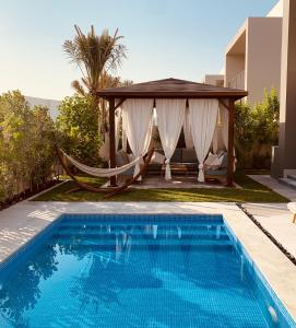 迪拜The Sunshine Villa的一个带吊床和凉亭的游泳池