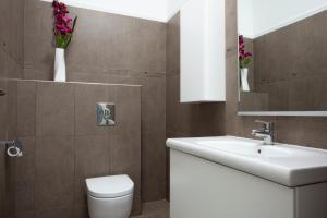 马林斯卡Luxury apartments Vila Carissa的一间带水槽、卫生间和鲜花的浴室