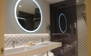安道尔城Suites Plaza Hotel & Wellness的浴室设有水槽和墙上的两面镜子