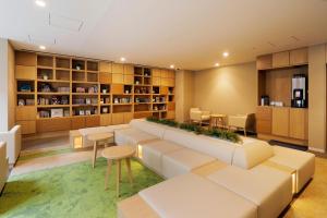 札幌JR Inn Sapporo Kita 2 Jo的一个带大沙发、桌子和书架的图书馆