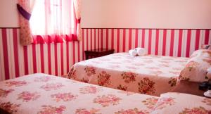 圣欧费米亚拉默齐亚阿格利特玛瑟利亚里斯酒店的一间卧室配有两张红色条纹床