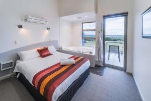 奥尔巴尼Cosy Corner Sea View Apartments的一间卧室配有一张床,浴室设有浴缸