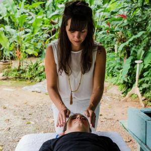 坎布里Casa Bacarirá - Floresta com Yoga e Café da Manhã Vegano的女人在床上躺着,正在剪男人的头发