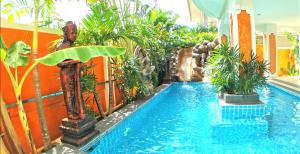 南芭堤雅JOOPLAND Luxury Pool Villa Pattaya Walking Street 6 Bedrooms的植物和游泳池的酒店游泳池
