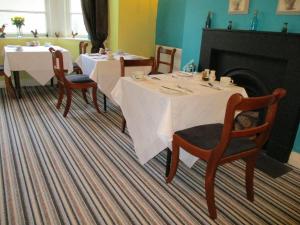 托基Cranborne Guest Accommodation Exclusively for Adults的一间带2张桌子和椅子的用餐室以及壁炉