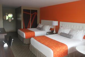 金斯顿Howard Johnson Inn by Wyndham Kingston的酒店客房,设有两张带橙色墙壁的床