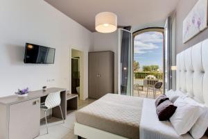 里米尼奥古斯特亚别墅酒店的一间带一张床和一张书桌的卧室以及一个阳台