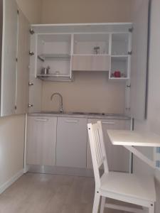 恩波利Affittacamere Stazione Empoli的白色的厨房配有白色椅子和水槽