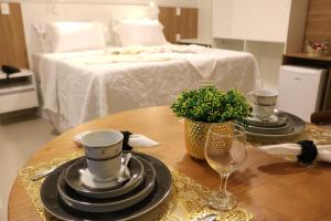德尔米鲁戈韦亚Bristol Aline Alagoas的一张桌子,上面有盘子和玻璃杯,还有一张床