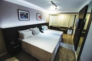 巴拉奈里奥-坎布里乌Santa Inn Hotel的酒店客房设有两张床和电视。