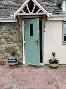 纽敦Lletty Ann wynn at Fraithwen Cottages的两棵盆栽植物的房子的前门