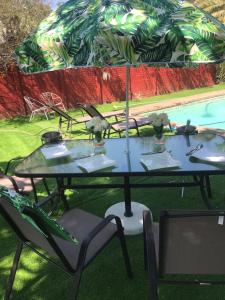 昆斯敦Beverley Hills guesthouse的游泳池旁配有桌椅和遮阳伞